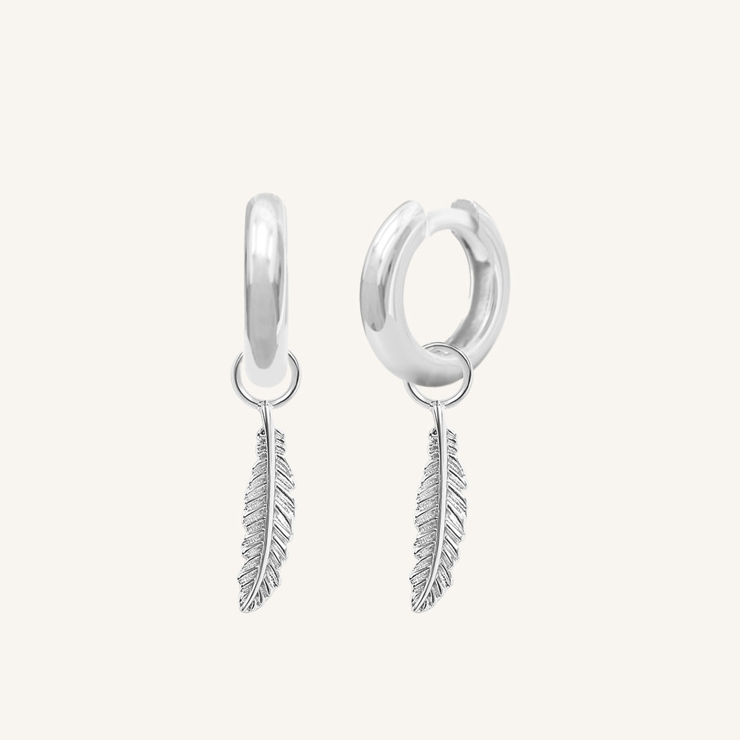 A set of two silver hoop charms with a feather design, on silver hoops