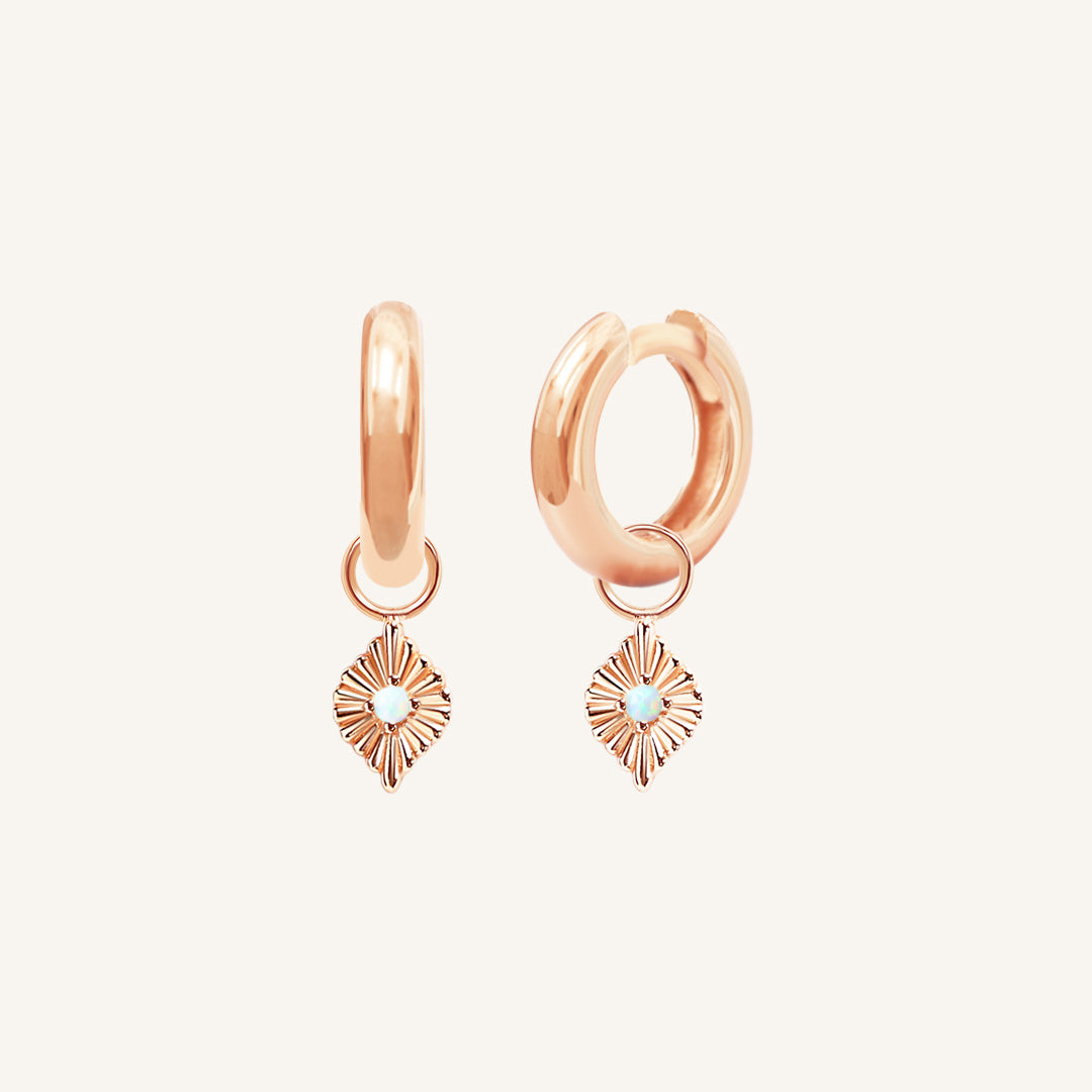 A pair of rose hoops with diamond shaped hoop charms featuring a faux opal