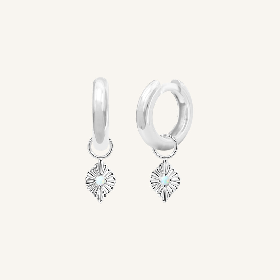 A pair of silver hoops with diamond shaped hoop charms featuring a faux opal