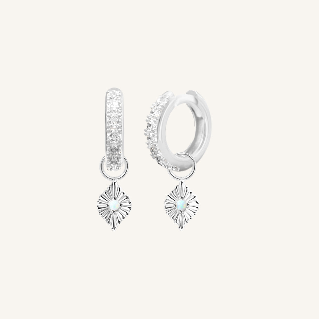 A pair of silver hoop earrings with cubic zirconia and diamond shaped hoop charms featuring a faux opal