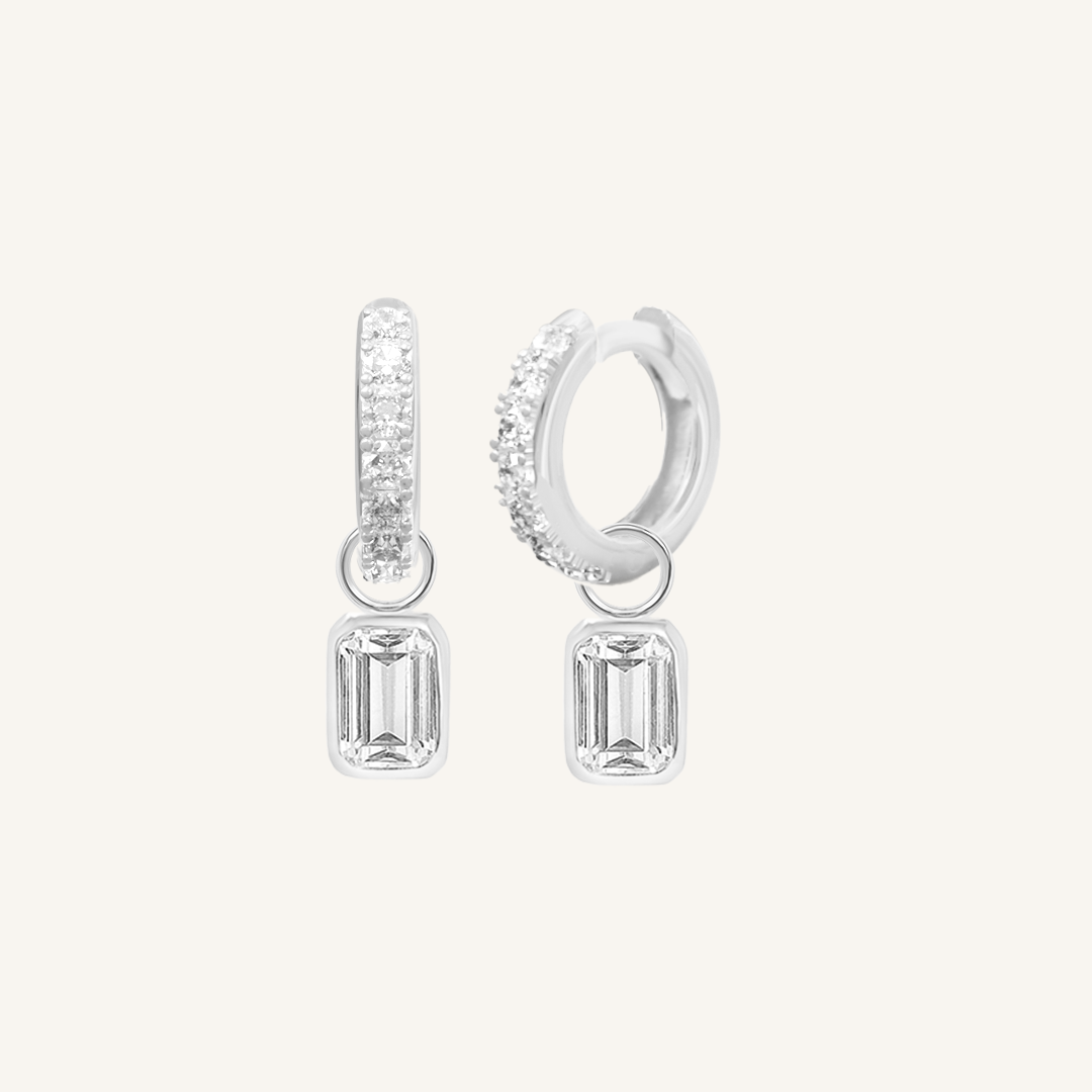 A pair of silver-tone radiant crystal hoop earrings with charm drops.