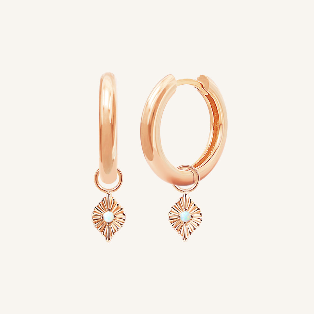 A pair of rose hoops with diamond shaped hoop charms featuring a faux opal
