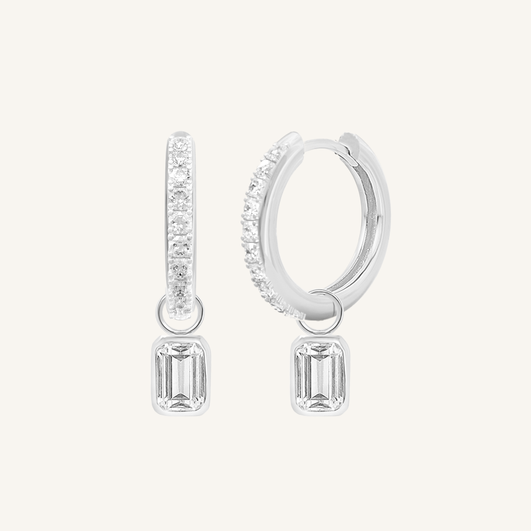 A pair of silver-tone radiant crystal hoop earrings with charm drops.