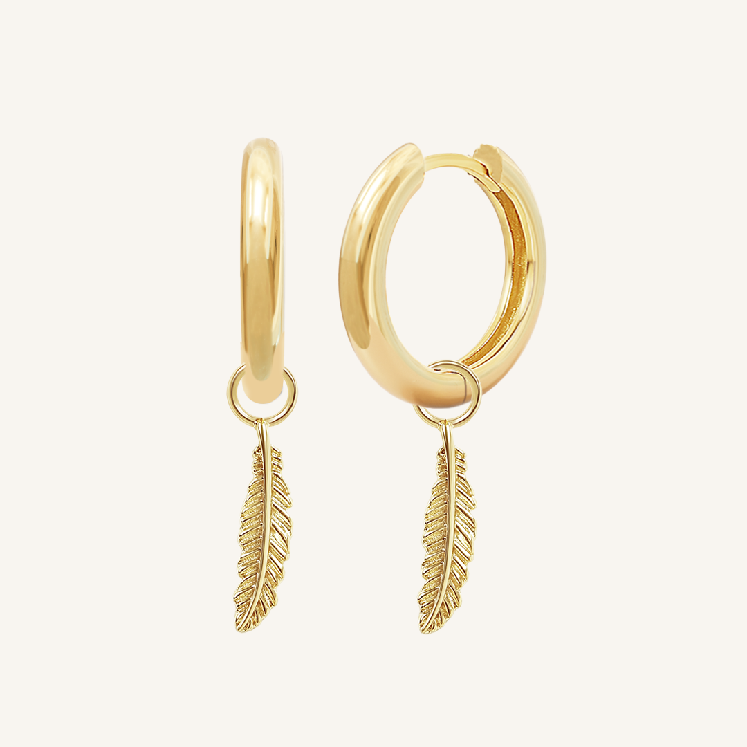A pair of gold-colored hoop earrings with delicate feathers attached to the hoops.