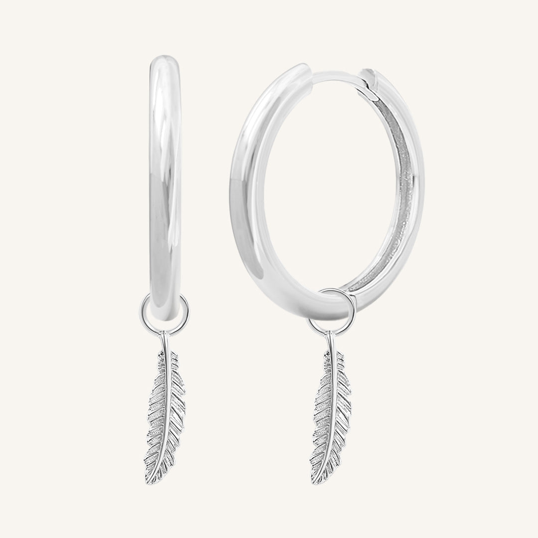 A pair of gold-colored hoop earrings with delicate feathers attached to the hoops.