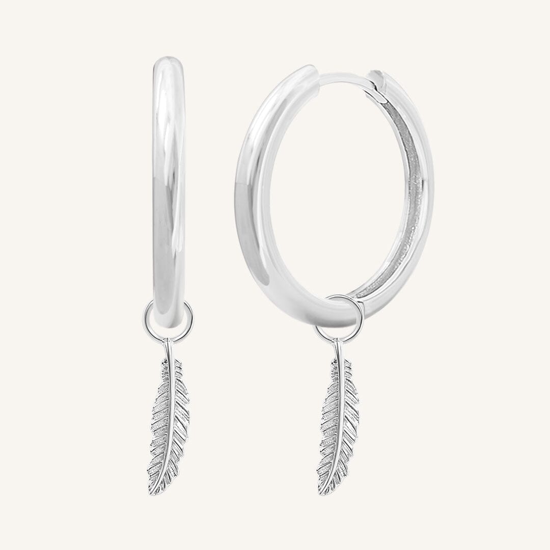 A pair of gold-colored hoop earrings with delicate feathers attached to the hoops.
