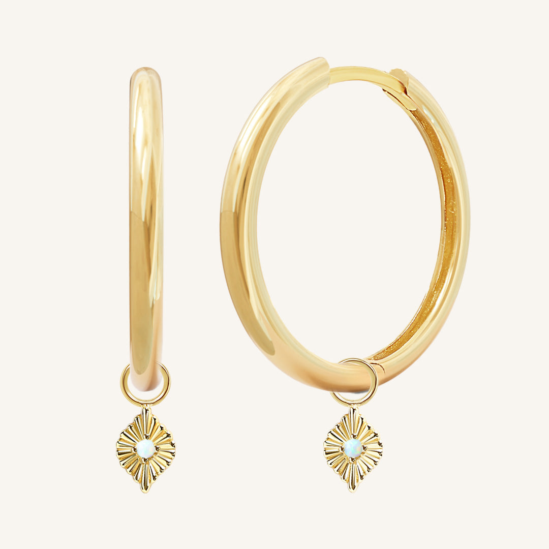 A pair of gold hoops with diamond shaped hoop charms featuring a faux opal