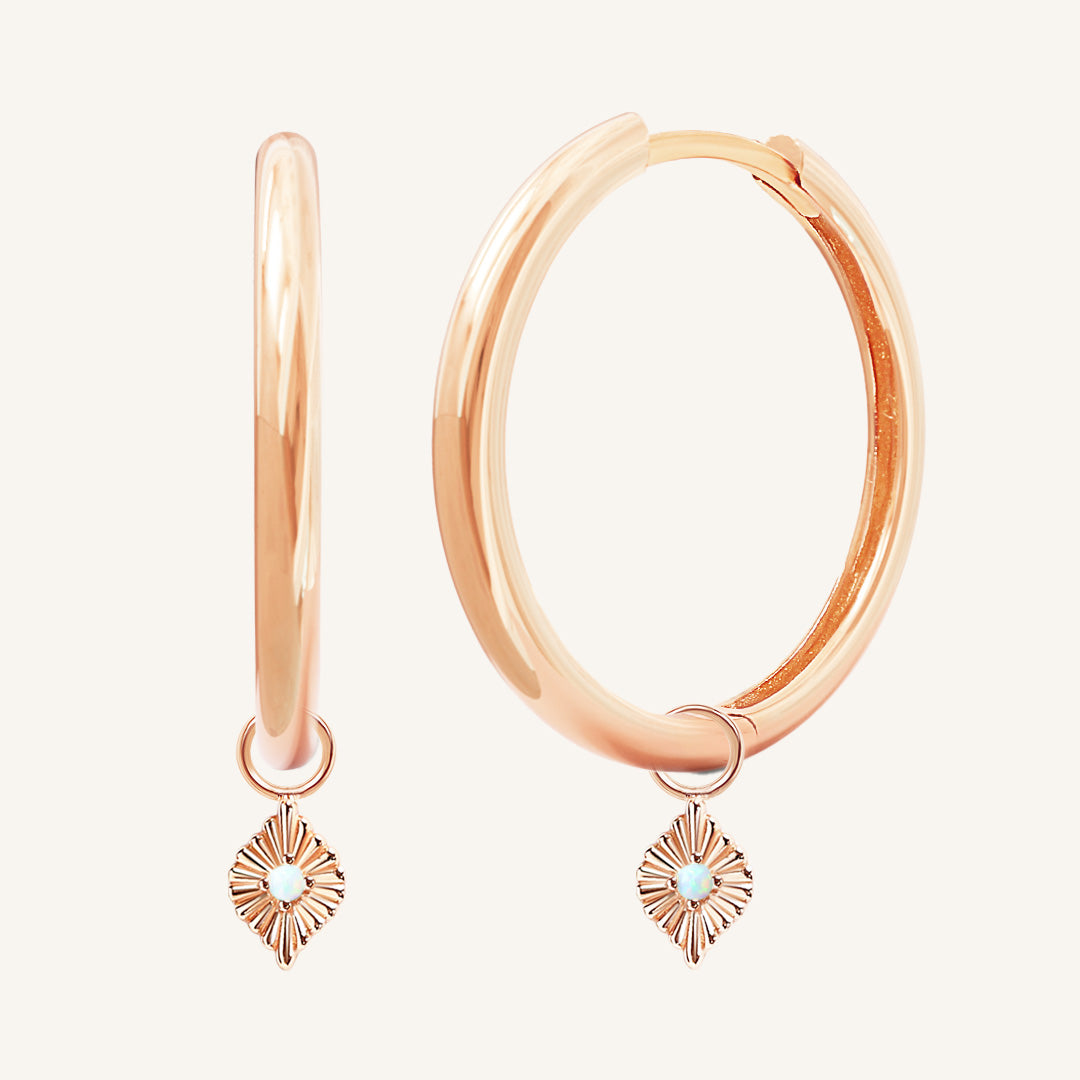 A pair of rose hoops with diamond shaped hoop charms featuring a faux opal