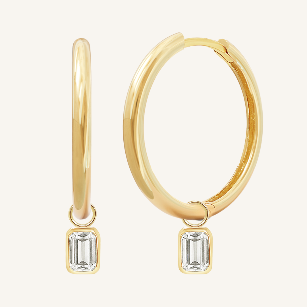 A pair of gold-colored hoop earrings with transparent crystal embellishments.