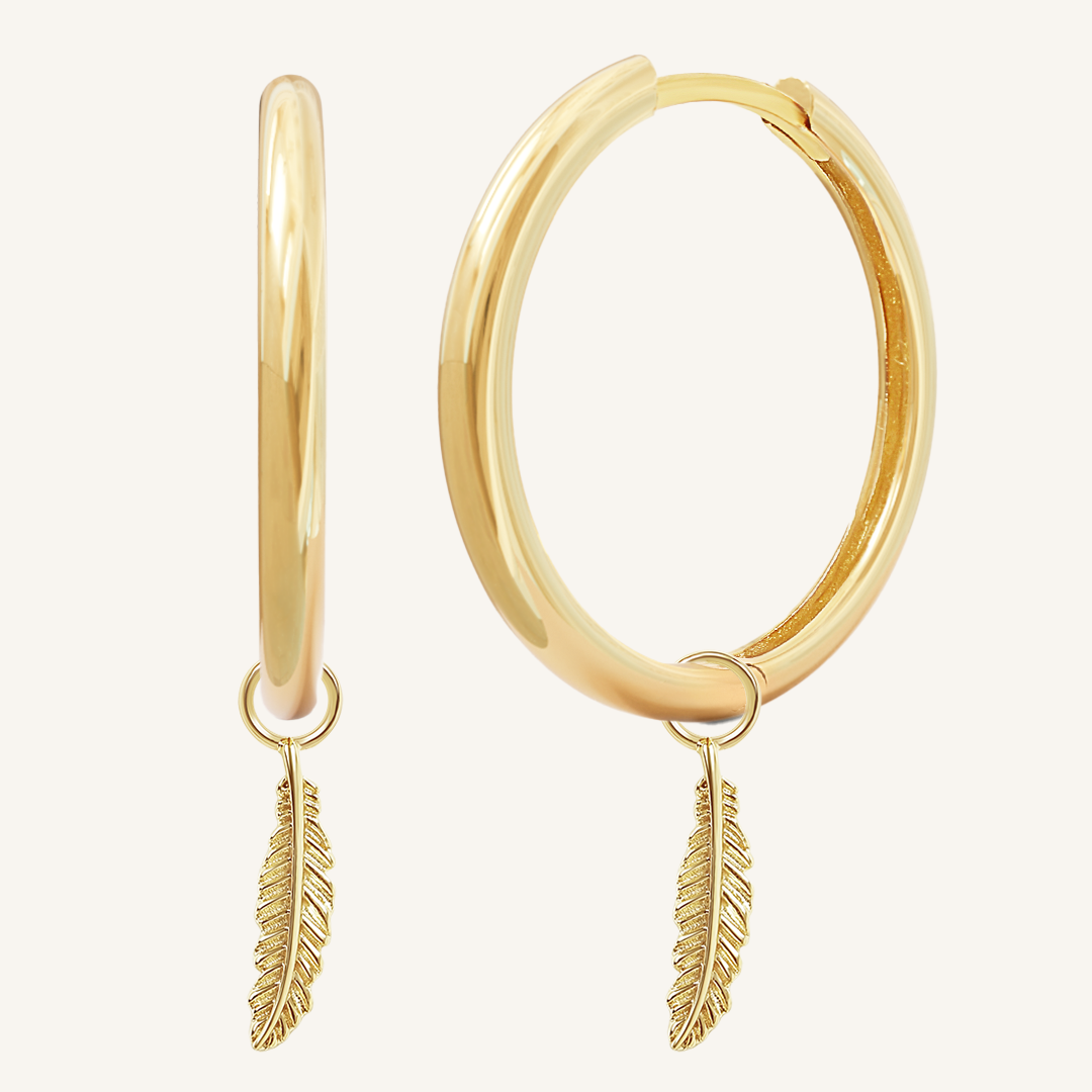 A pair of gold-colored hoop earrings with delicate feathers attached to the hoops.