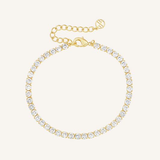 A gold-coloured tennis bracelet with clear cubic zirconias linked together, featuring a extender chain for adjustable length.