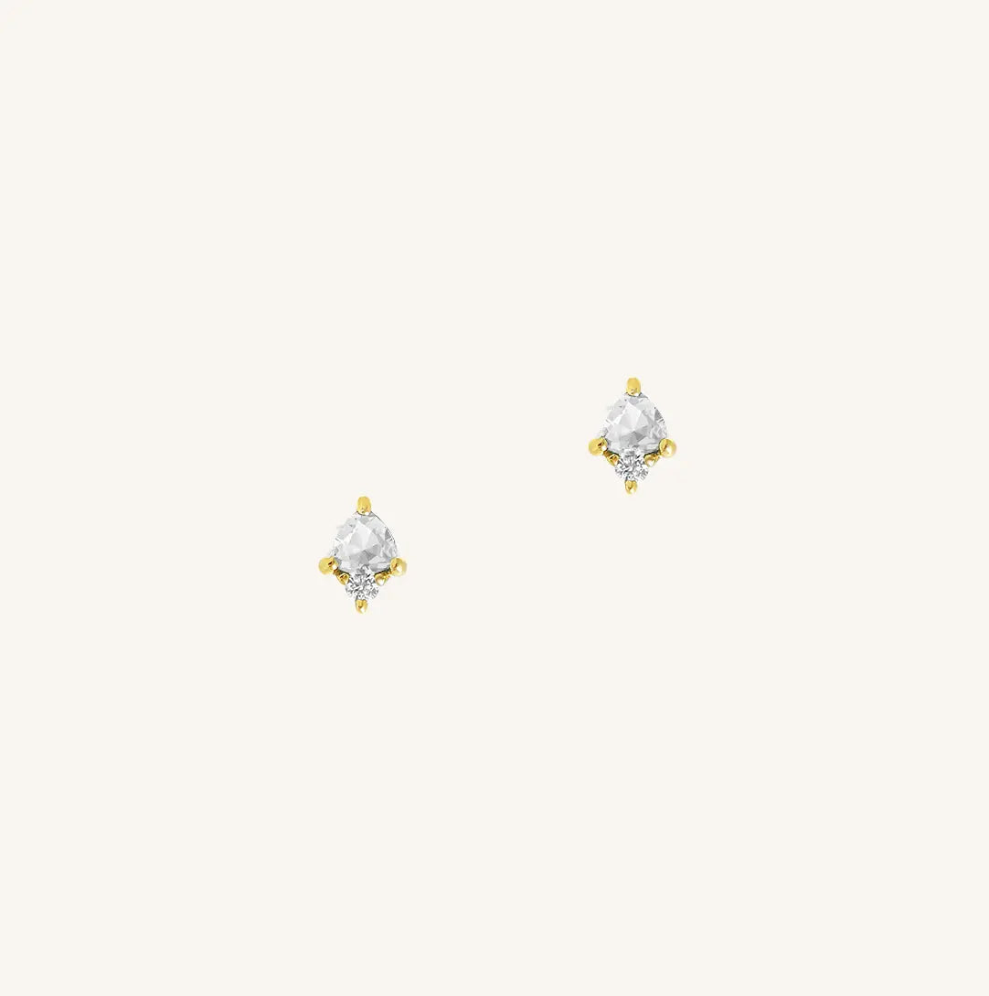 A gold pair of stud earrings featuring a white cubic zirconia, representing April.