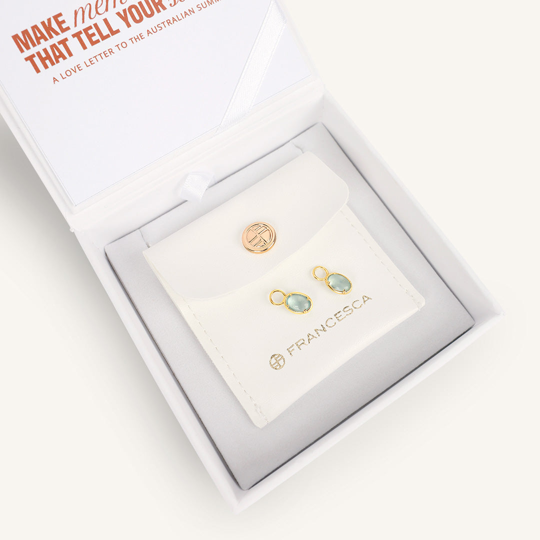 Gold and blue hoop charms in a white box with 'Francesca' branding.