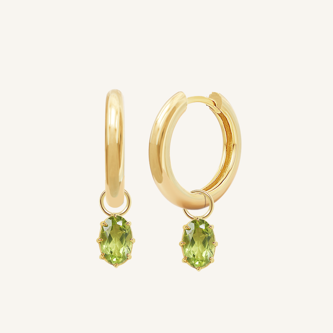 A pair of gold-tone hoop earrings with olive green charms attached to them.