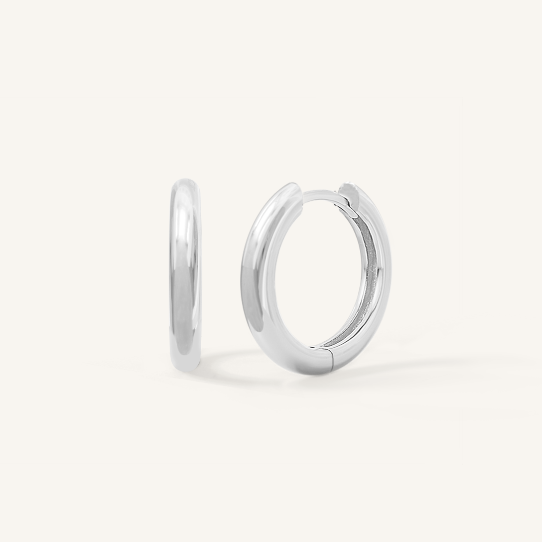 A pair of silver-colored hoop earrings on a white background