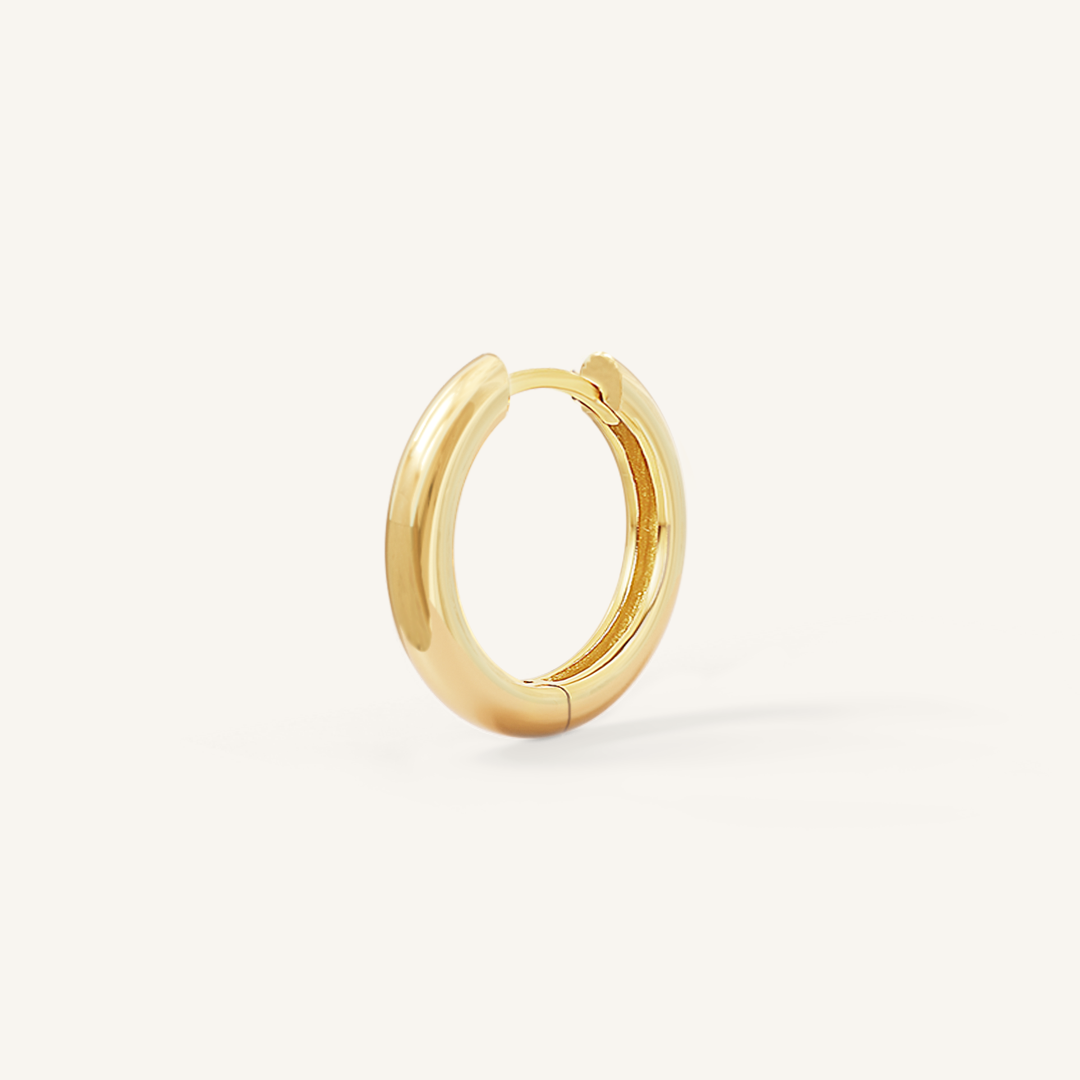 A gold hoop earring on a white background