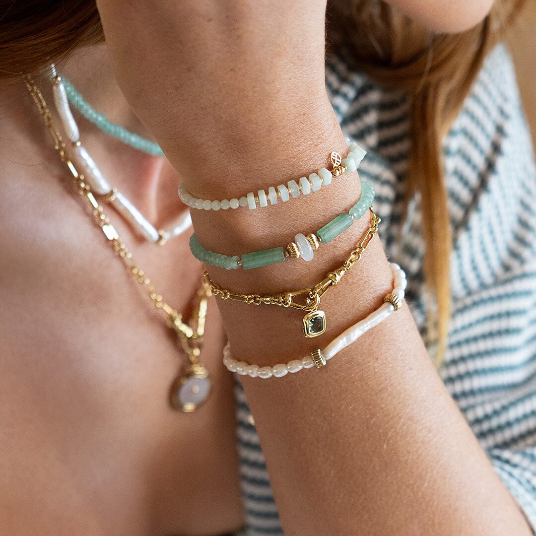 Close-up of a person's wrist wearing multiple bracelets with a blurred background