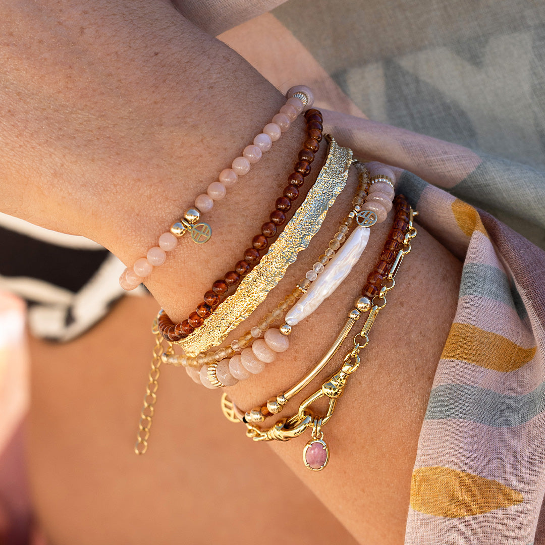 Close-up of a person's arm wearing multiple bracelets with a blurred background