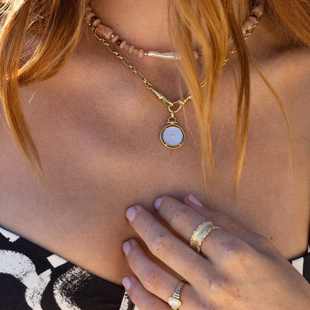 Close-up of a person wearing gold necklaces and rings with a blurred background