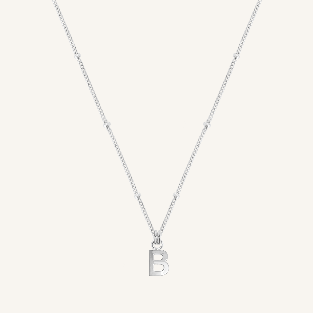 Silver necklace with a 'B' pendant on a light gray background