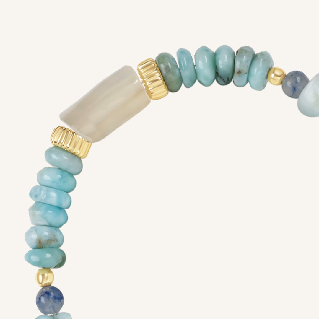 Beaded bracelet with turquoise, beige, and gold beads on a white background