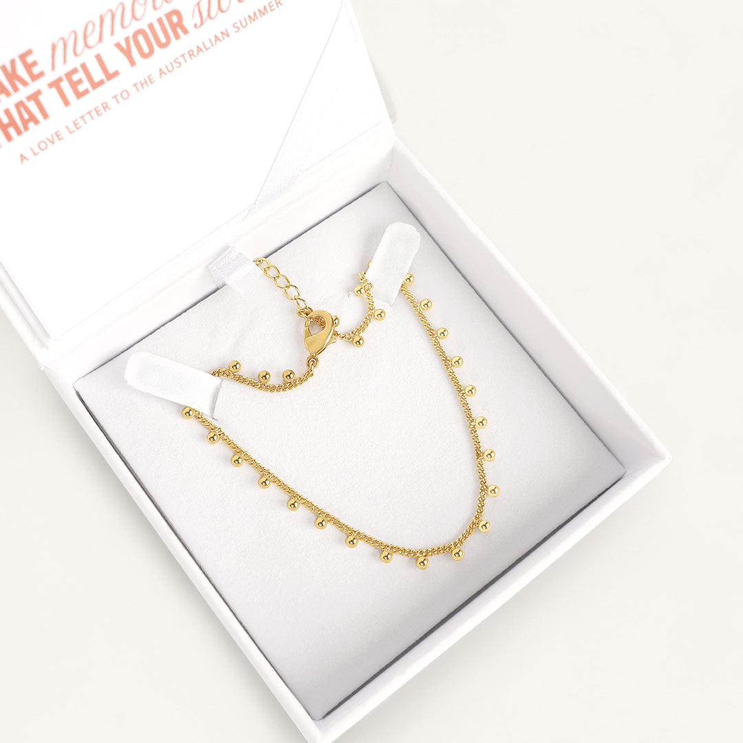 Gold anklet, displayed in white box