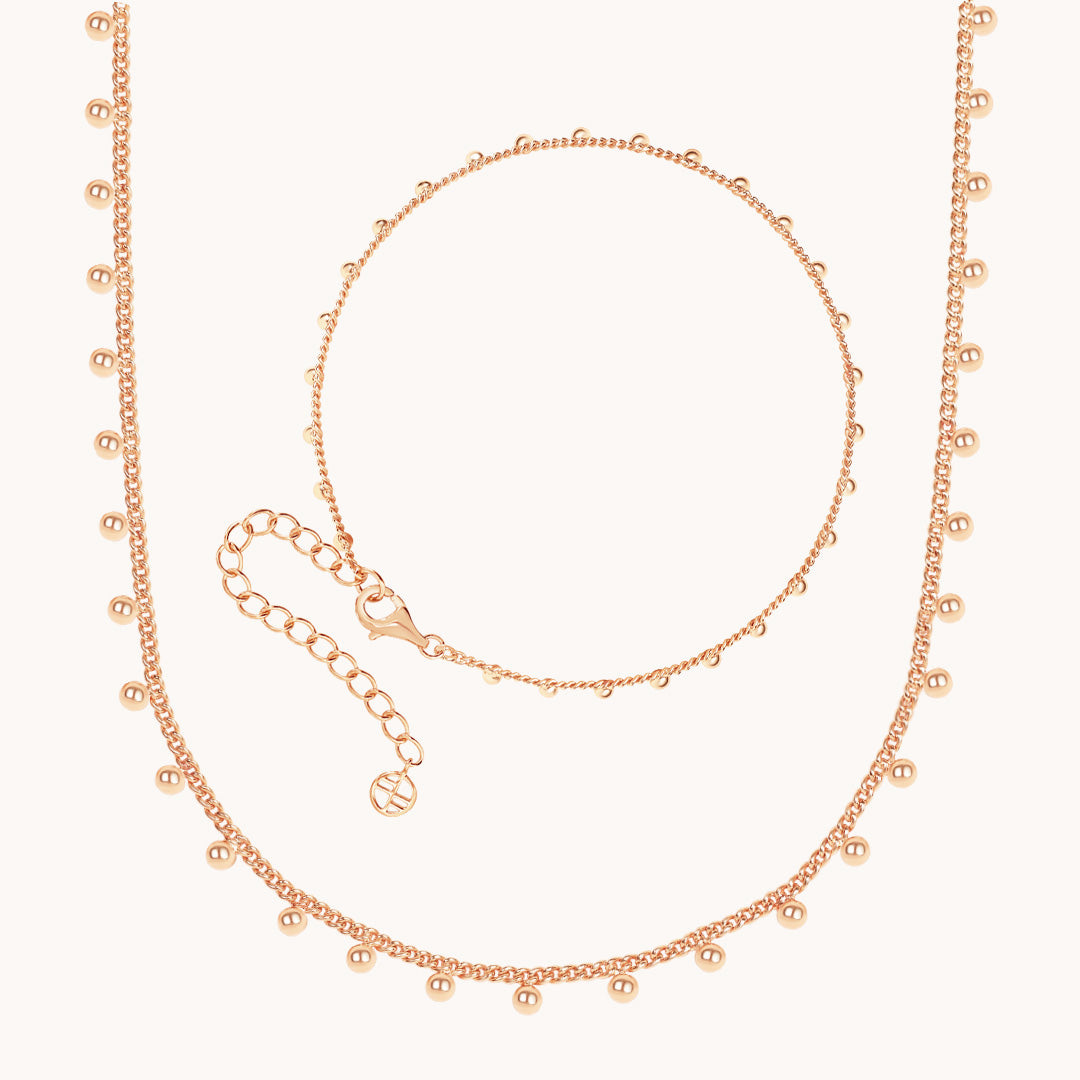 Rose gold necklace and bracelet set on a white background