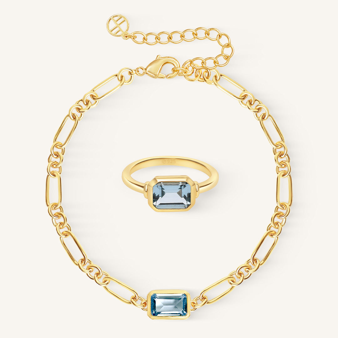 Gold bracelet and ring with blue gemstones on a white background
