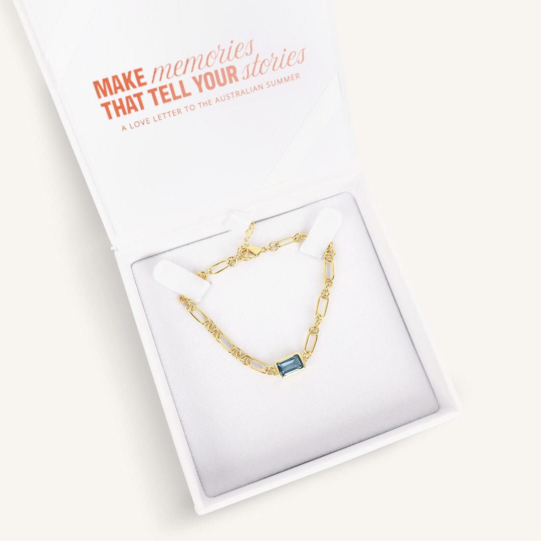 Gold bracelet with a blue gemstone, in a white box