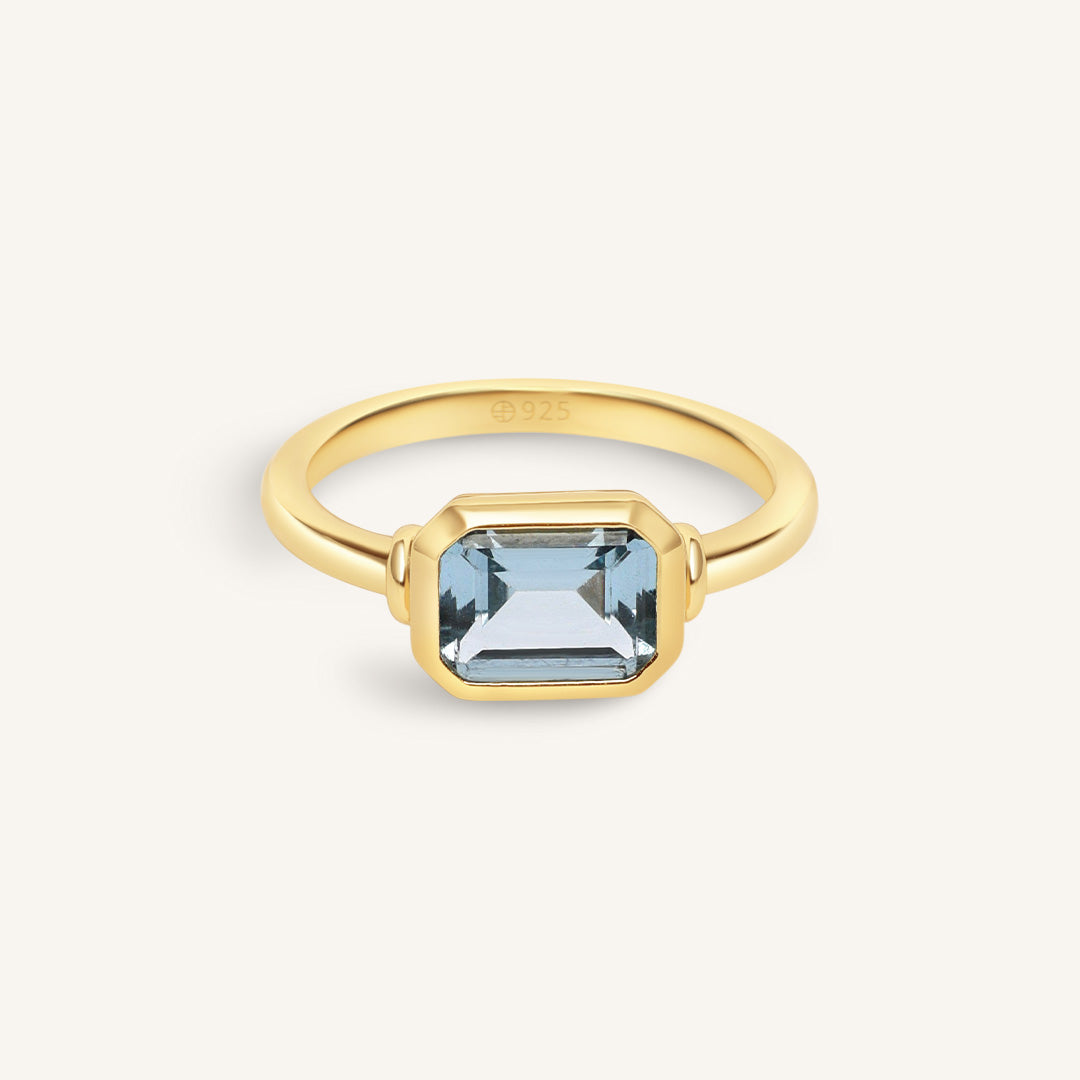 Gold ring with a blue gemstone on a white background