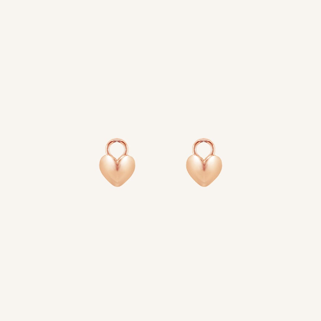 A pair of heart-shaped rose hoop charms against a white background