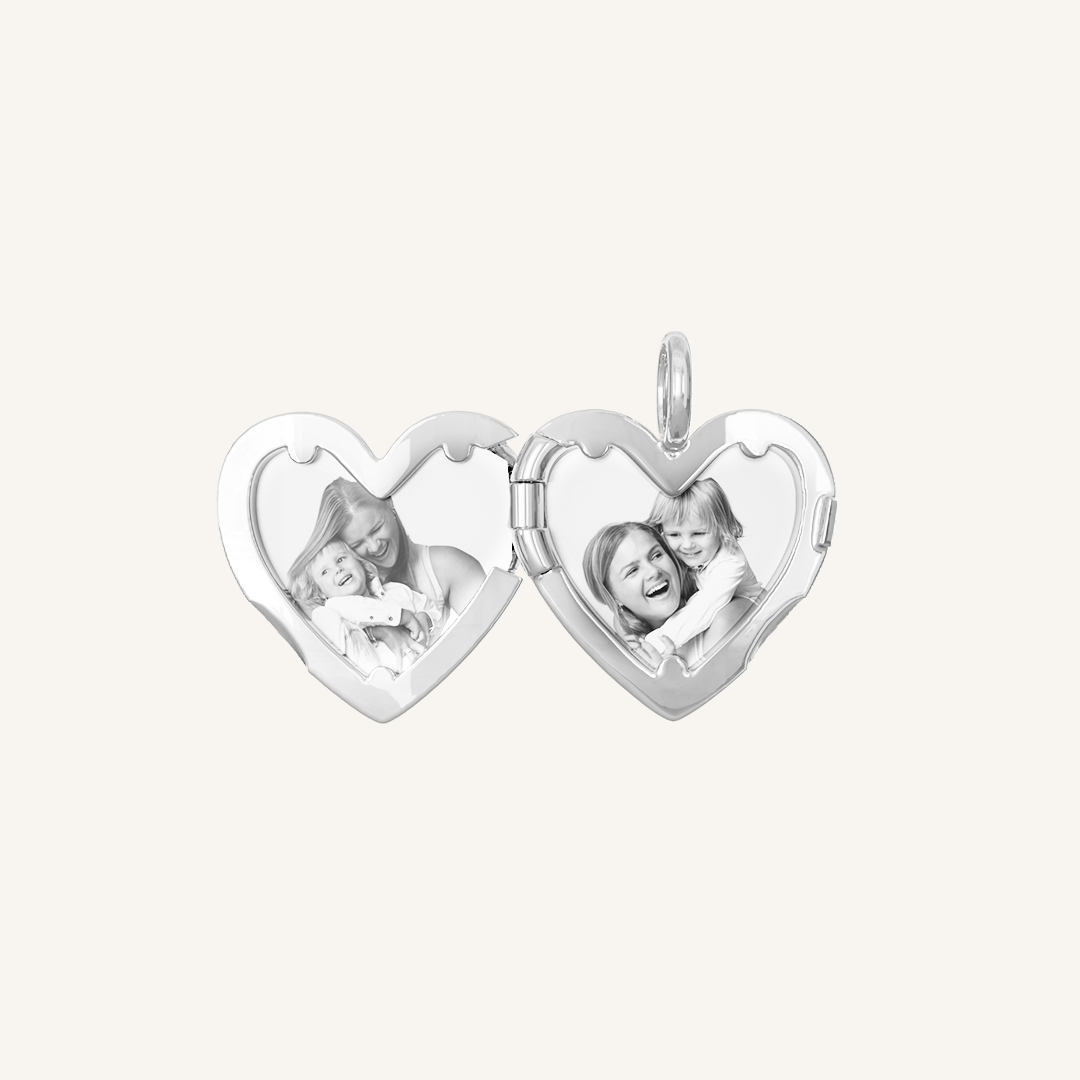 A silver heart-shaped photo locket with two images inside