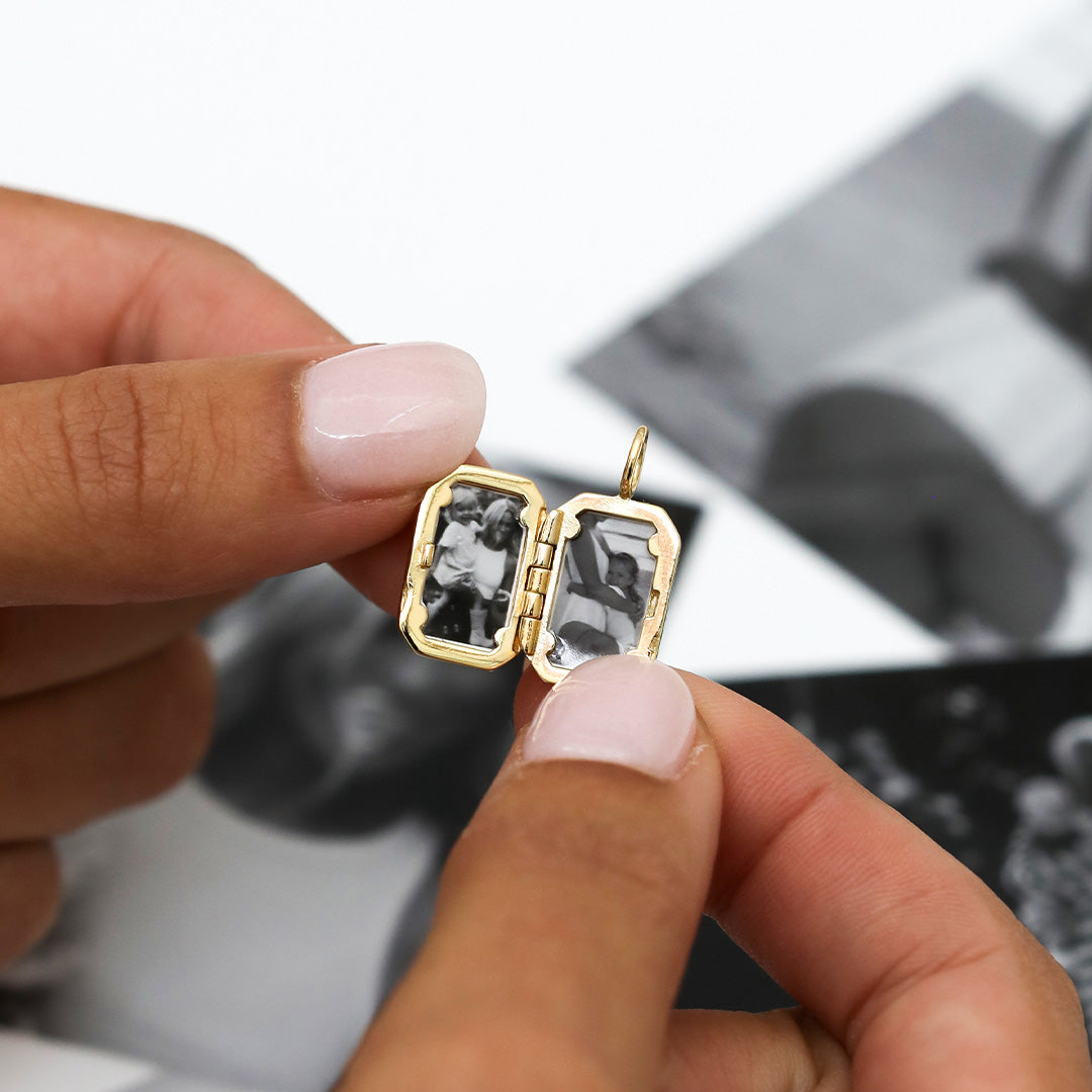 Close up on open gold bevel locket held in models fingers