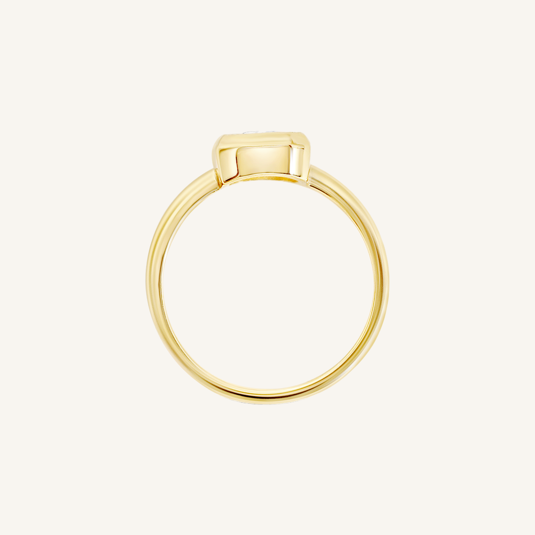A gold-coloured ring with a white cubic zirconia, bezel set in a rectangular frame with a smooth, polished band, side profile