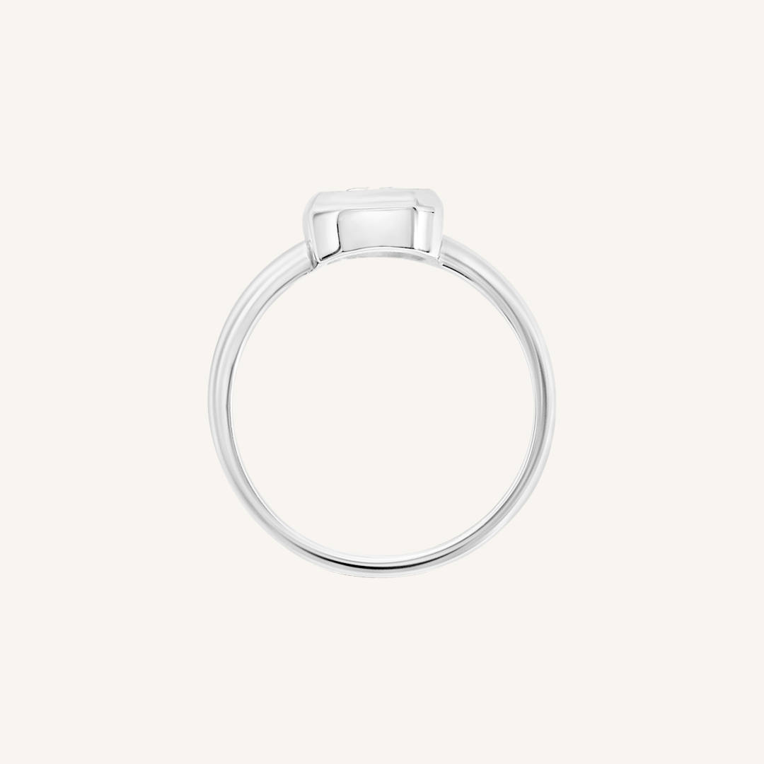 A silver-coloured ring with a white cubic zirconia, bezel set in a rectangular frame with a smooth, polished band, side profile