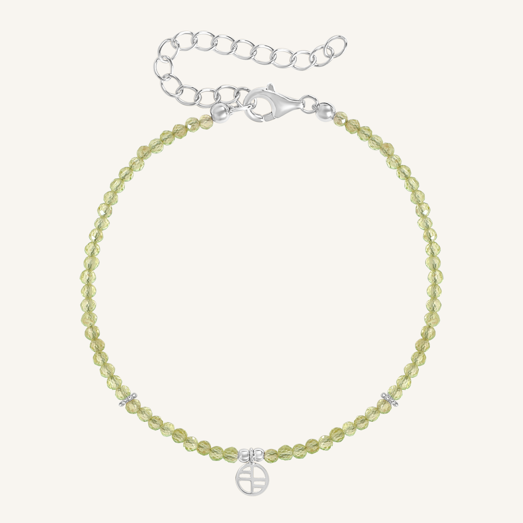 A beaded bracelet with green stones and a silver metal clasp, representing the August birthstone.