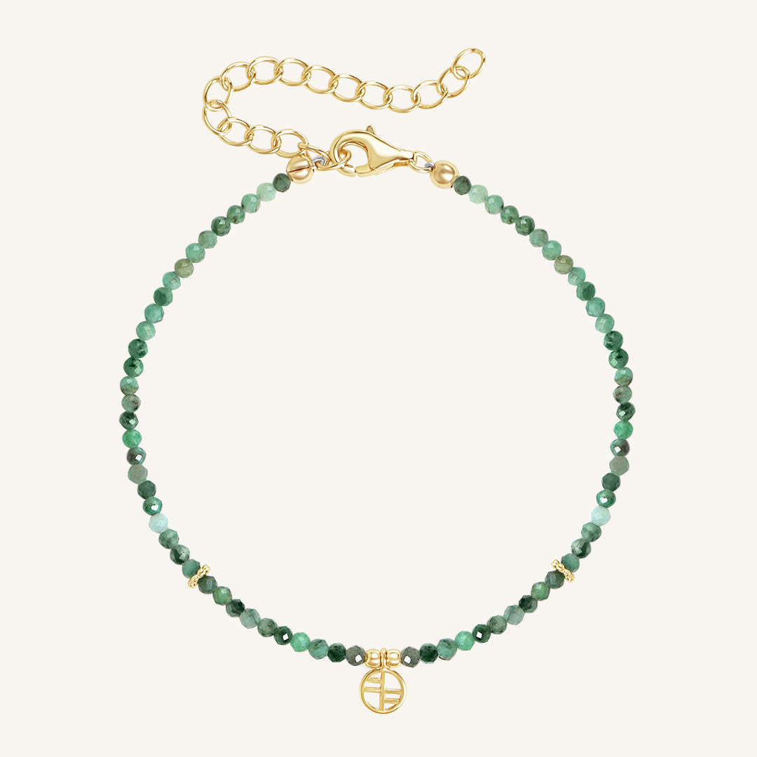 A beaded bracelet with green gemstones and a gold-tone clasp and charm.