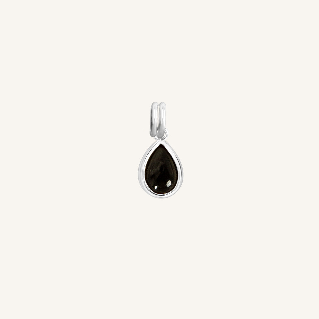 A silver charm with a teardrop-shaped black onyx stone.