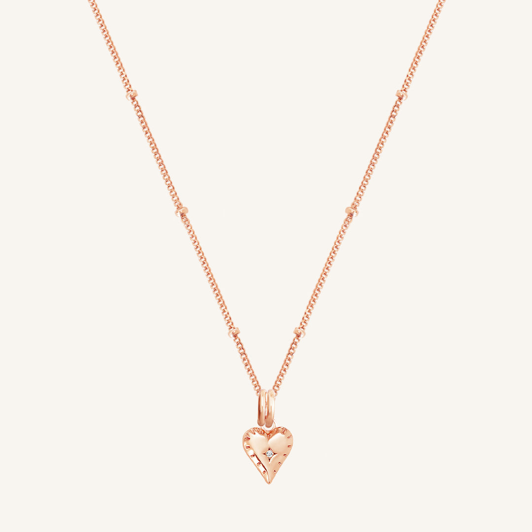 A gold-tone heart-shaped charm necklace with an adjustable chain.