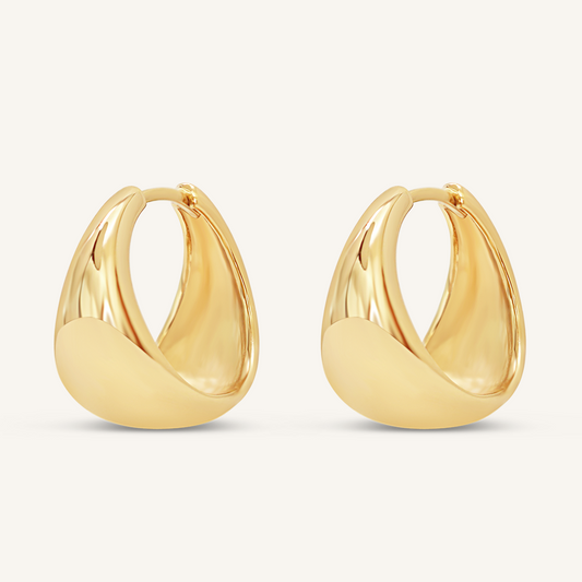 A pair of gold-colored chunky hoop earrings on a white background.