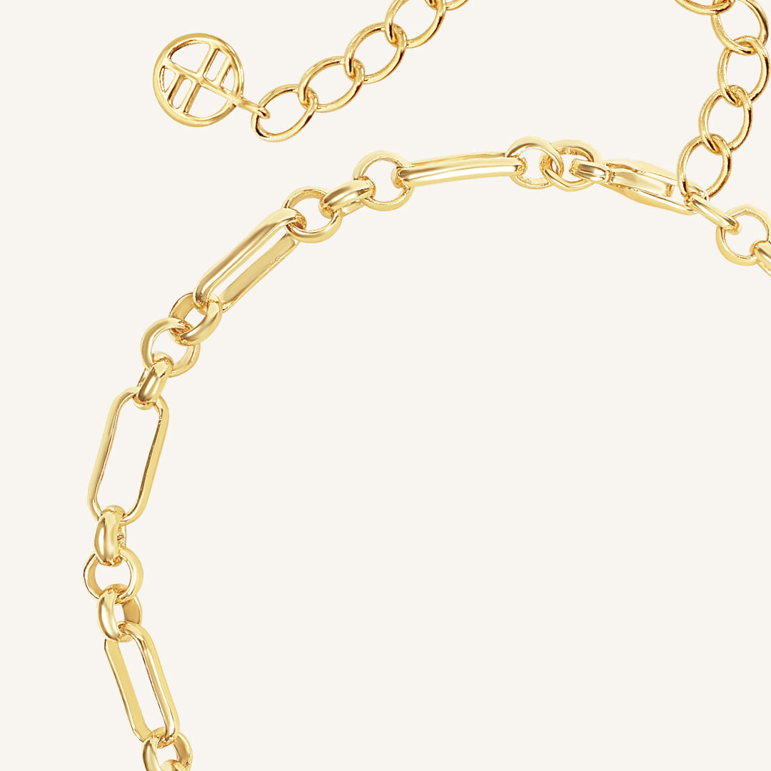 Gold chain bracelet on a light beige background