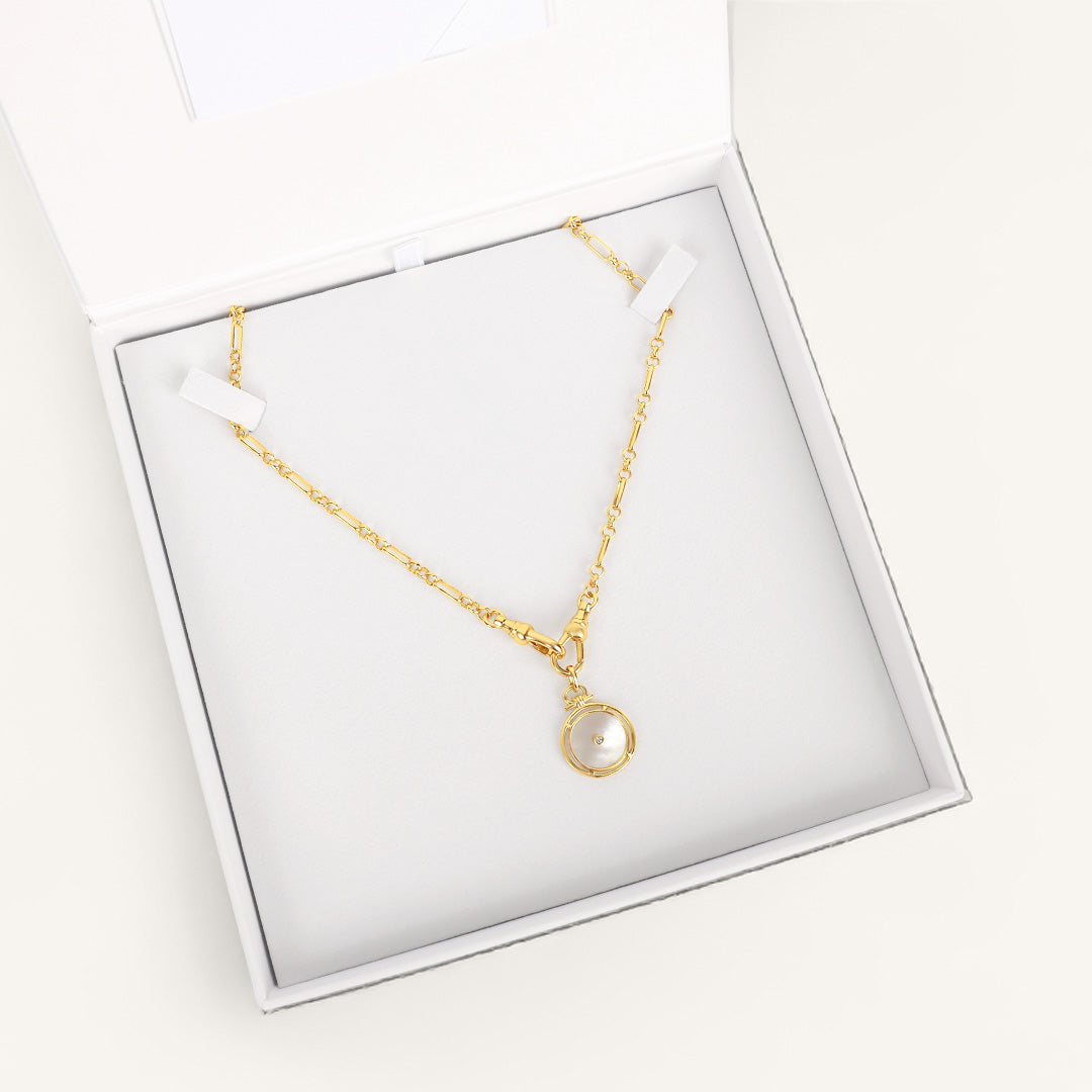 Gold necklace with a pearl pendant in a white box on a white background