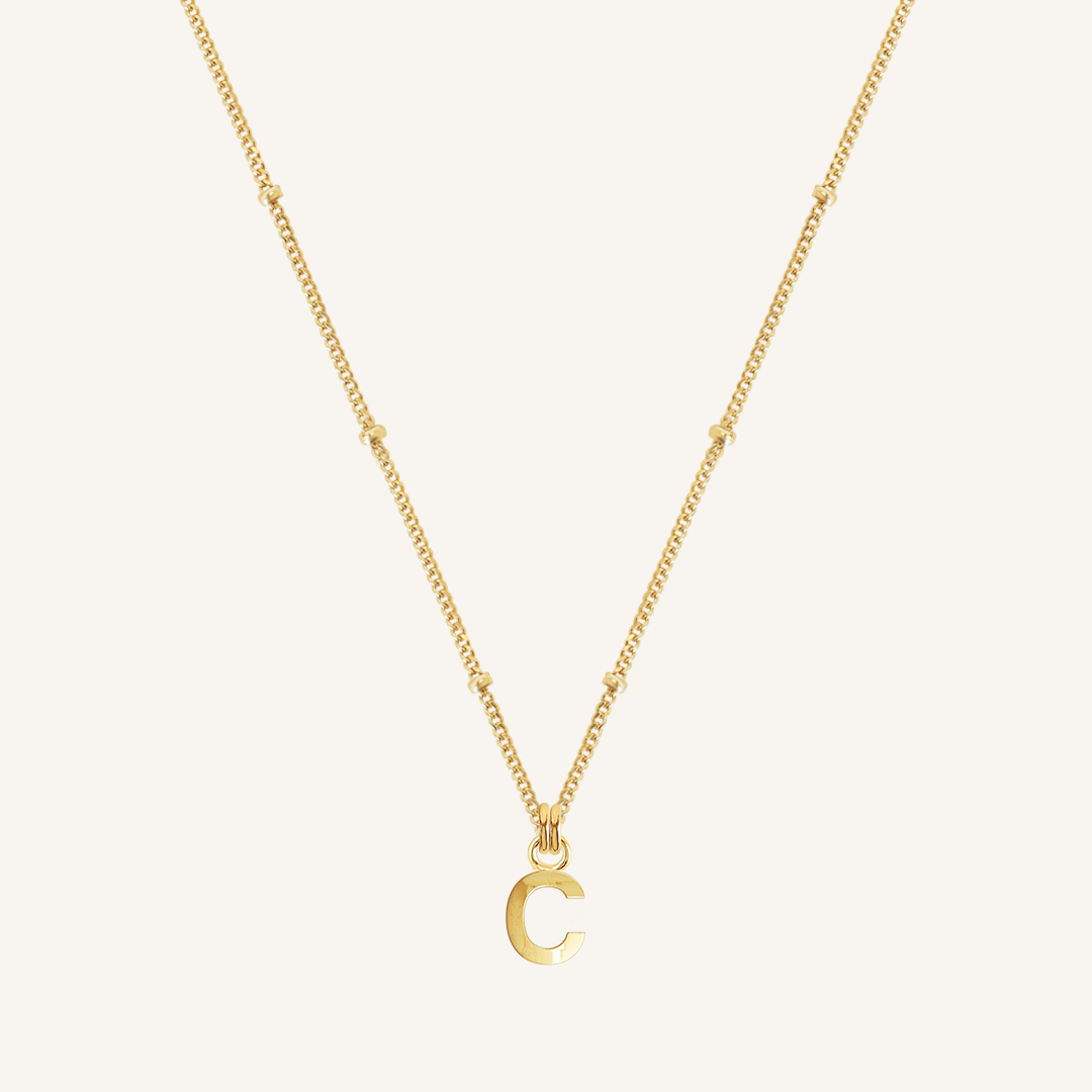 Gold necklace with a 'C' pendant on a white background