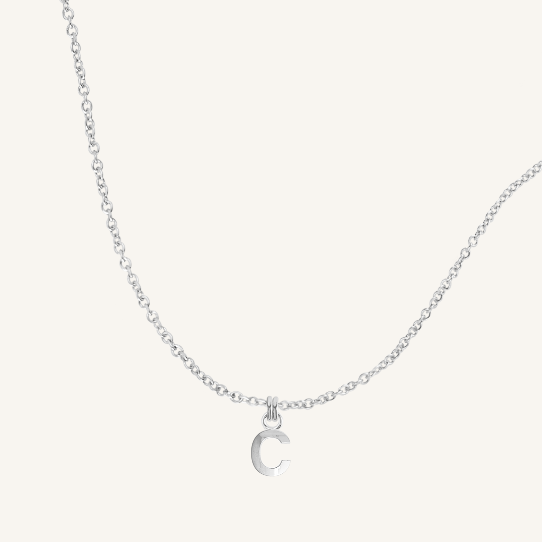 Silver necklace with a C letter pendant on a white background