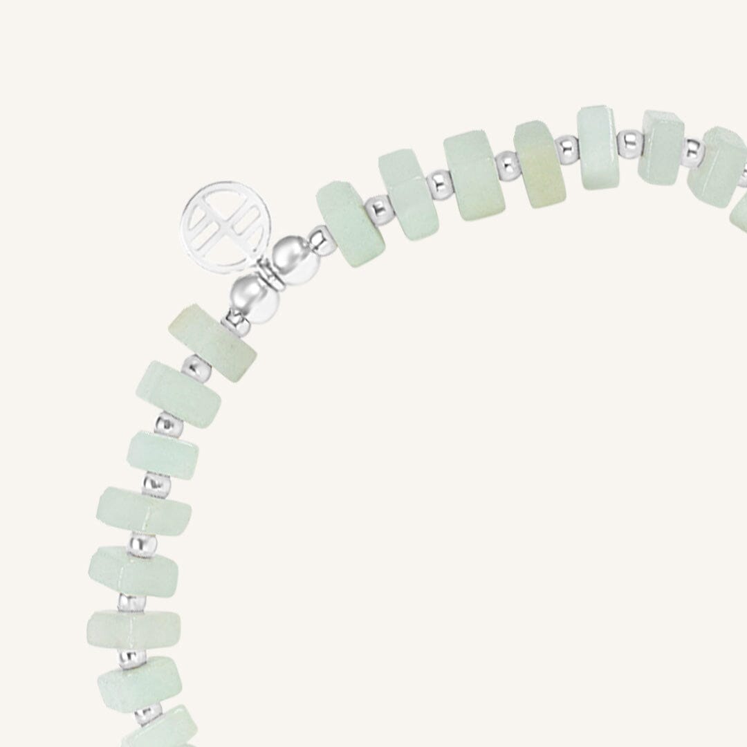 Bracelet with light green beads and silver accents on a white background