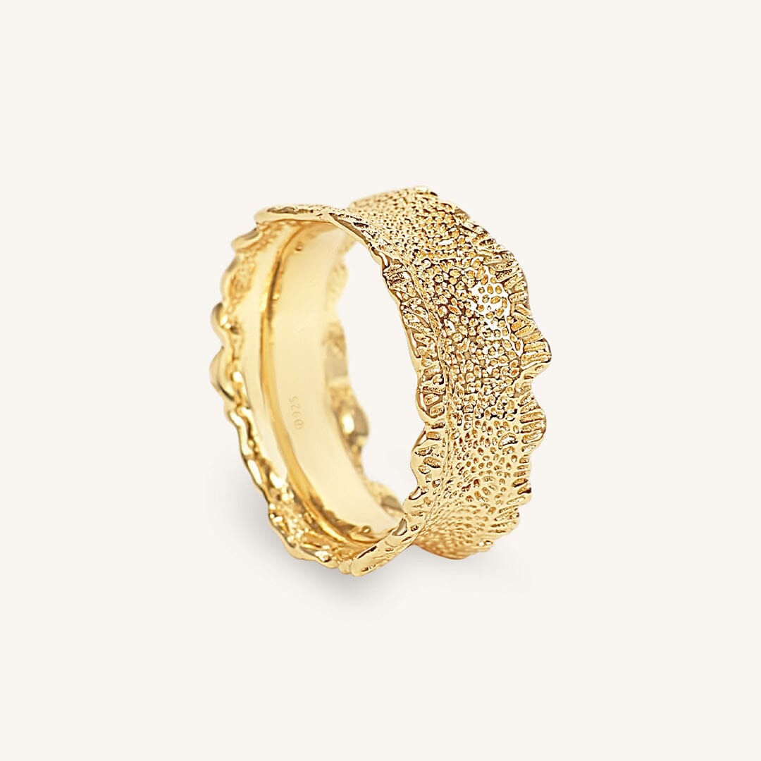 Gold ring with textured design on a white background