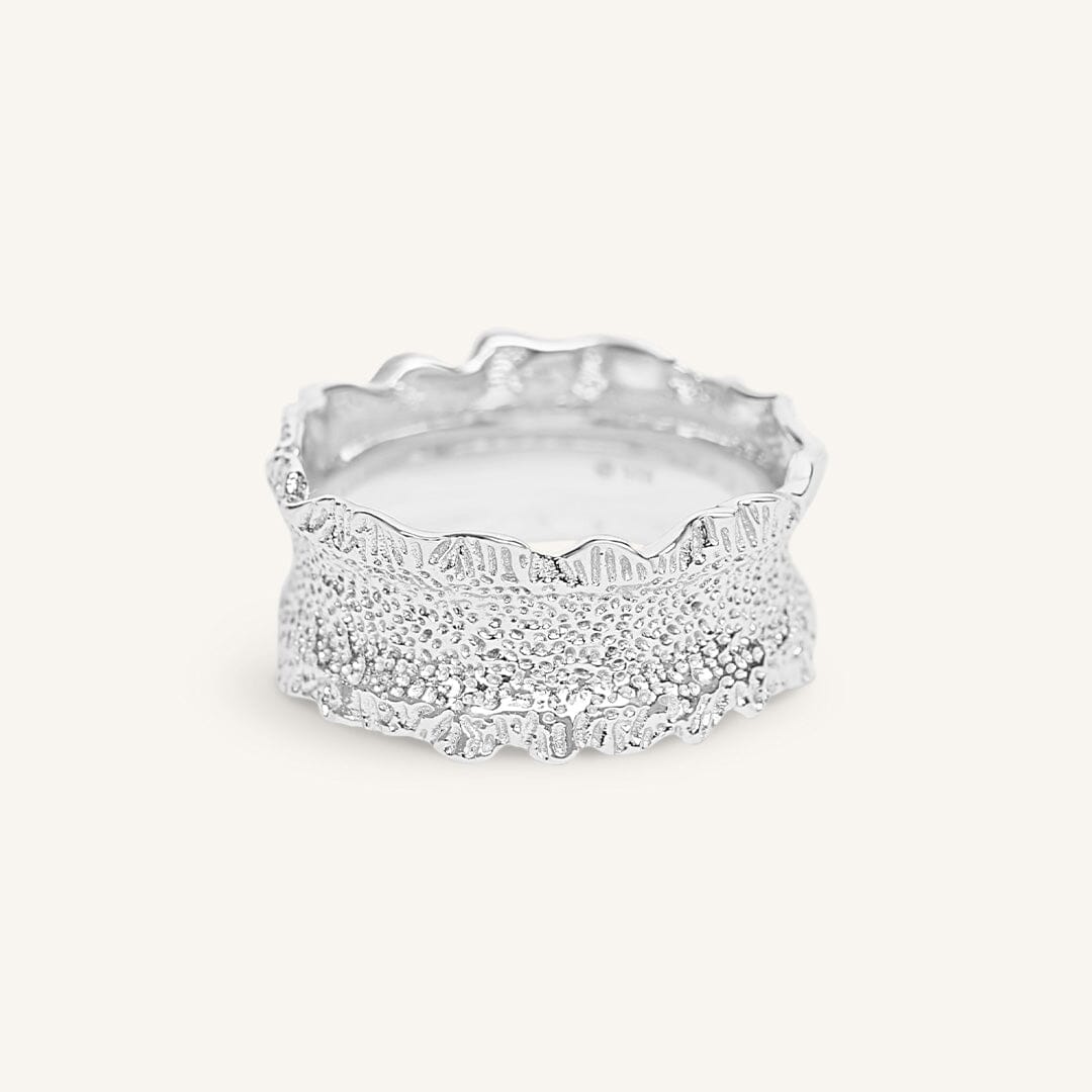 Silver ring with textured design on a white background