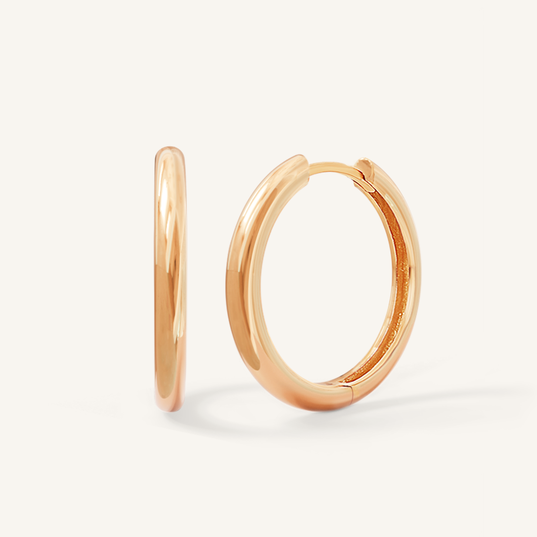 A pair of rose-tone hoop earrings on a white background