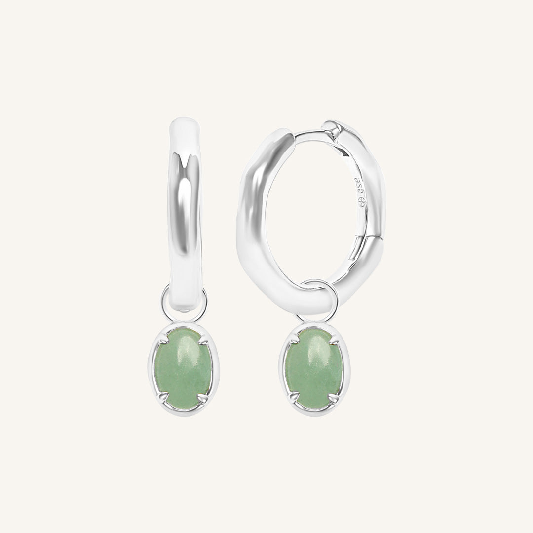 Silver hoop earrings with green gemstones on a white background