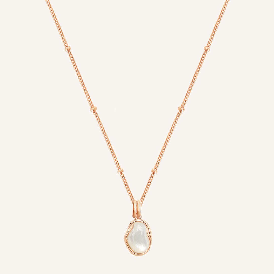 Rose gold necklace with a teardrop-shaped pearl pendant on a light beige background